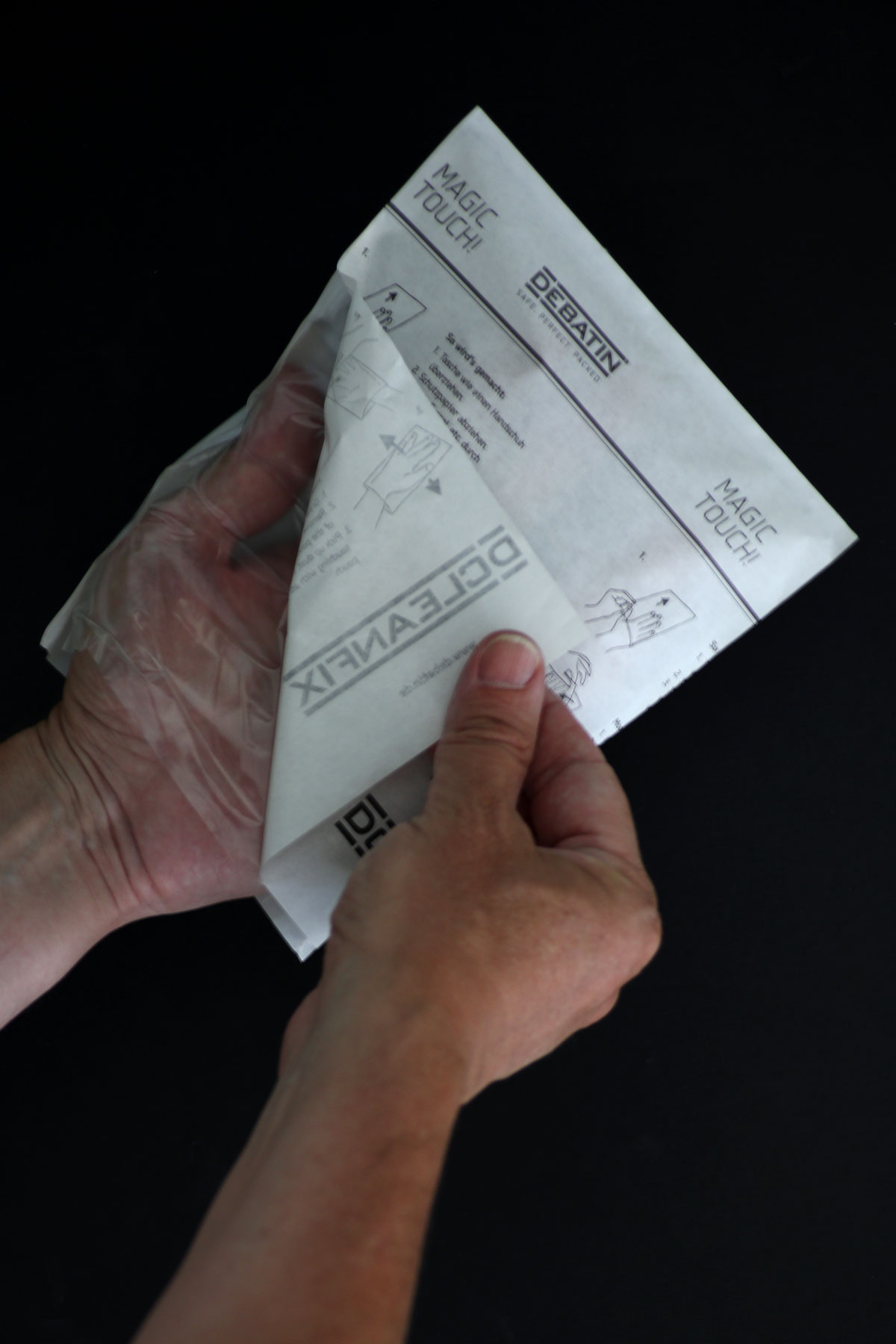 cleanfix_use Hands peeling off the protective paper of a CLEANFIX® bag, showing usage instructions and “Magic Touch!” print.