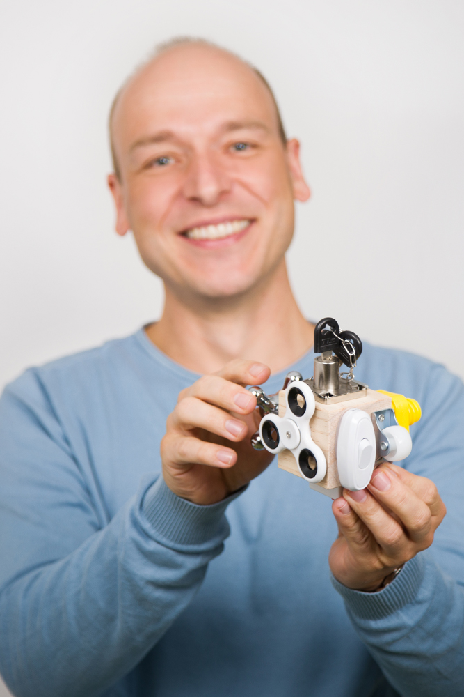 DEBATIN_Produktsparten_Headerbild_DEBADEINS_Tröber_Würfel Dr.-Ing. Oliver Tröber is holding a fidget cube in his hand.