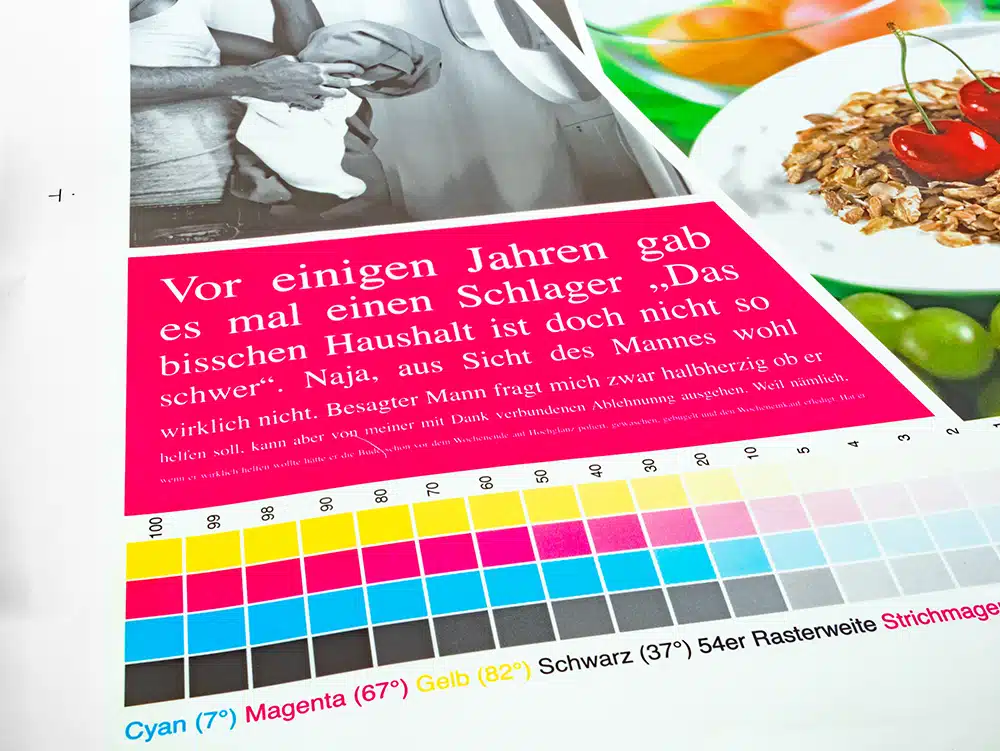 IMG_0118 Close-up of a DEBATIN print product created using the DEBAPRINT flexographic printing process. A section of a brochure shows text, a colour scale for print quality checks, and an image of cherries on muesli. The precise colours and fine printing reflect the exceptional quality of DEBAPRINT.