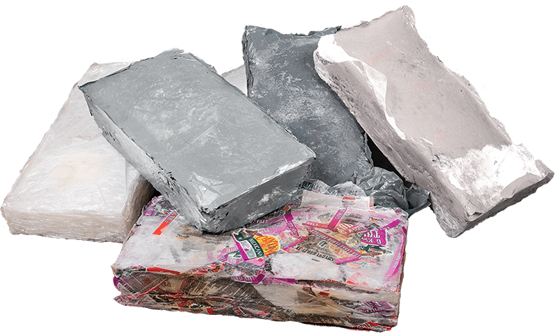 Close up view of a number of solid, irregularly shaped bales of thermally melted and compacted plastic, showing how the recycled material looks after being processed in a thermal baler.