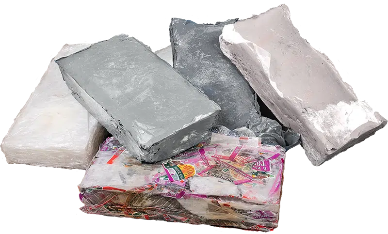 Gepresste Kunstofftaschen Close up view of a number of solid, irregularly shaped bales of thermally melted and compacted plastic, showing how the recycled material looks after being processed in a thermal baler.