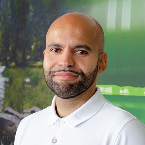 Portrait of Ernesto Bauer, a bald man with a beard wearing a white polo shirt and smiling slightly. He is Head of Customer Service at Debatin.