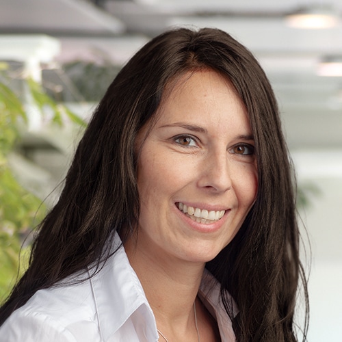 Close-up of Gabriele Hillenbrand, a smiling woman with long dark hair wearing a white shirt. She is Sales Consultant / Customer Service at Debatin.