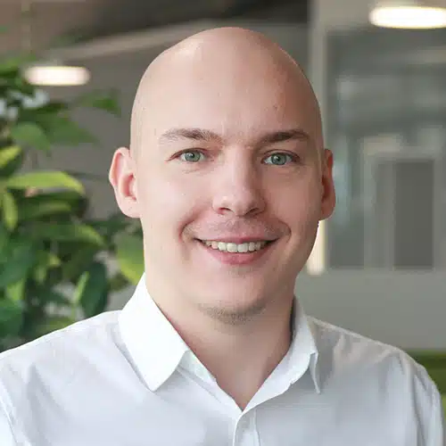 Close-up of Robin Fabry, a young man with short hair and glasses. He wears a dark shirt and smiles slightly at the camera. Robin Fabry works at DEBATIN.