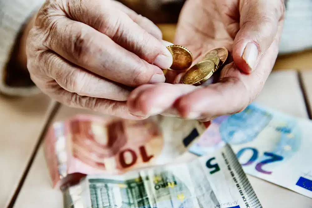 Older hands counting Euro coins over banknotes – symbolising cash dependency and participation in later life.